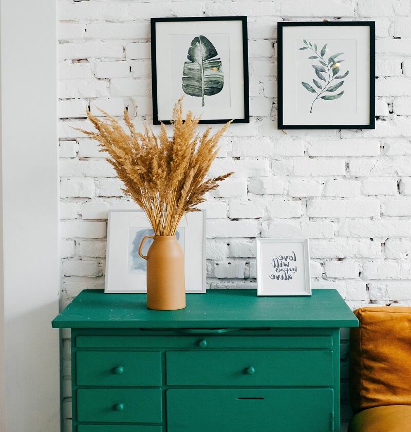 Farmhouse setting with wooden green table, photo frames and rustic brick background